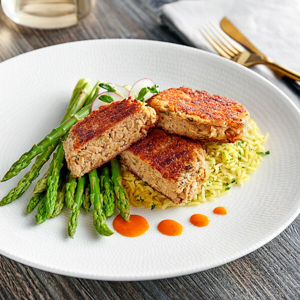 A plate with Mind Blown vegan crab cakes and asparagus on a table.