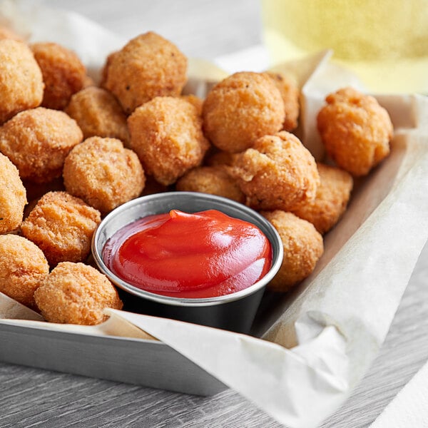 A bowl of fried food with a bowl of Red Gold tomato ketchup.