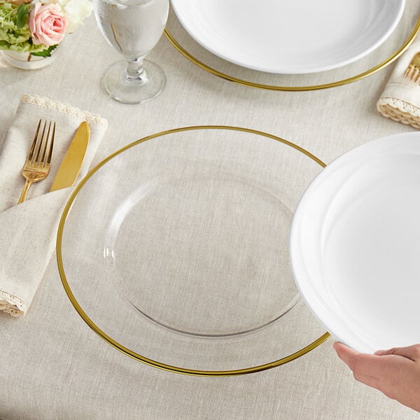 A person holding an Acopa round glass charger plate with a gold rim.