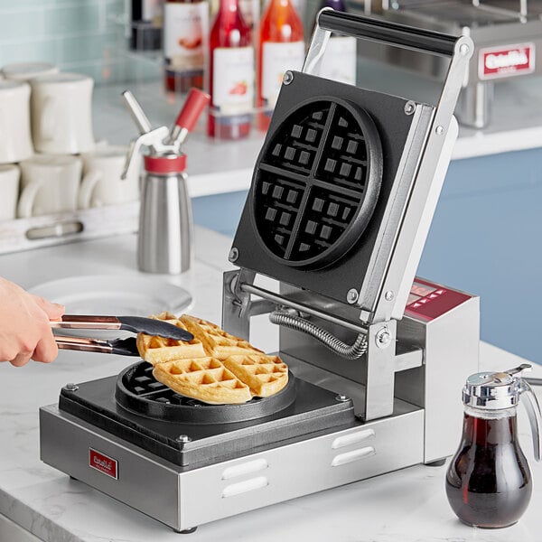 A person using an Estella Belgian waffle plate to make waffles in a waffle maker.