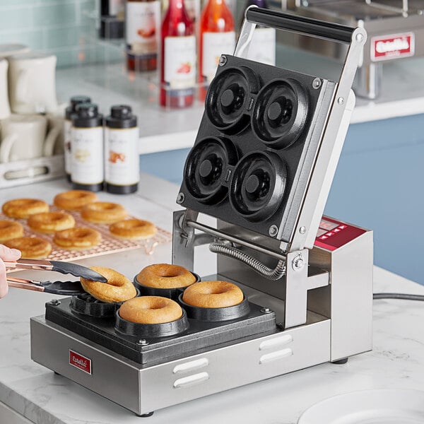 A woman using an Estella donut plate to make donuts in a machine.