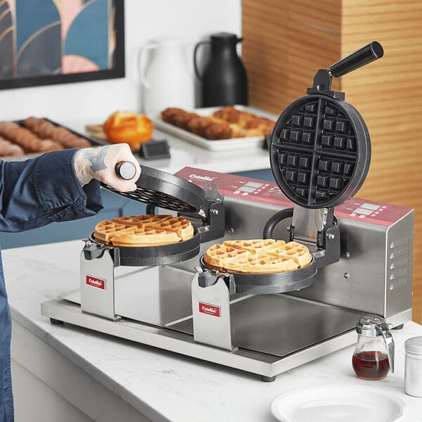A person using a Estella double Belgian waffle maker to cook waffles.