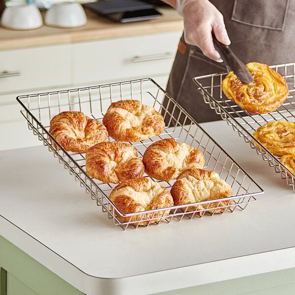 A person holding a pastry in a wire pastry basket.