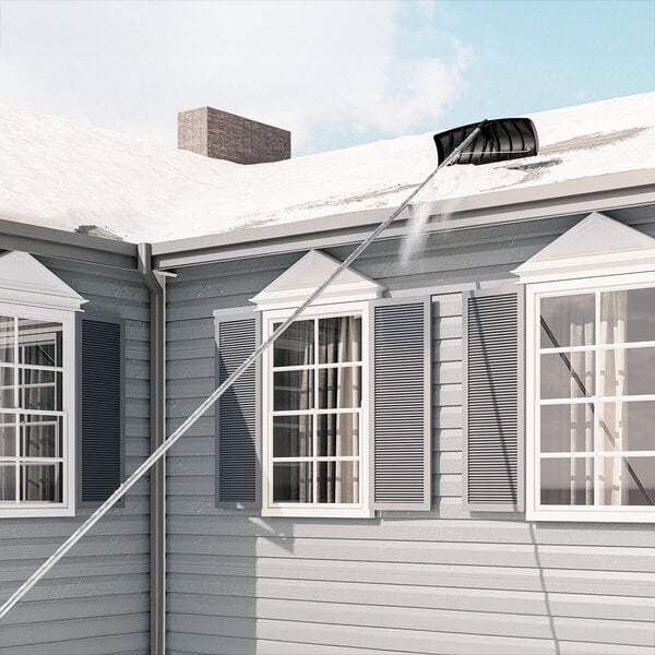 A man using a Suncast extendable roof rake to remove snow from a white roof.