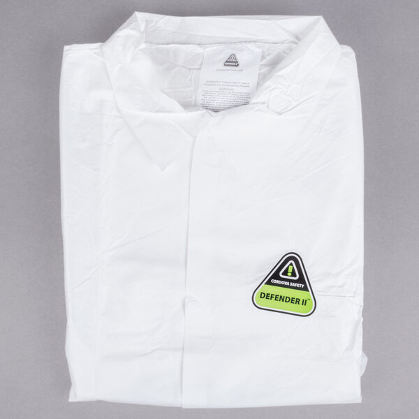 A folded white Cordova disposable lab coat with a yellow and green sticker.
