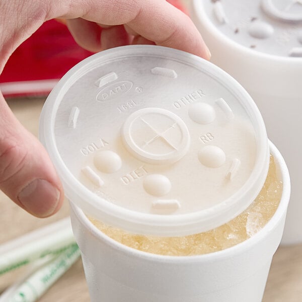 A hand putting a Dart Translucent plastic lid on a plastic cup.