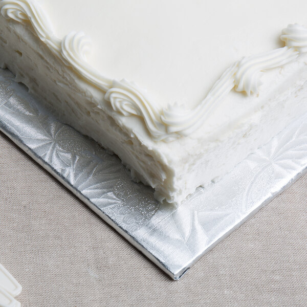 A white cake with frosting on a silver Enjay quarter sheet cake board.