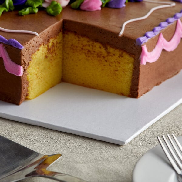 A white full sheet cake board with a chocolate cake and flowers on top.