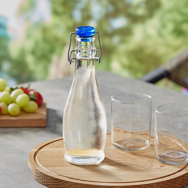 A Libbey oil and vinegar cruet with a wire bail lid and a glass of water on a table.