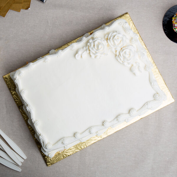 A white cake on a gold Enjay quarter sheet cake board.