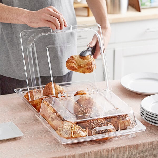 A person putting food in a Choice polycarbonate hinged dome cover.