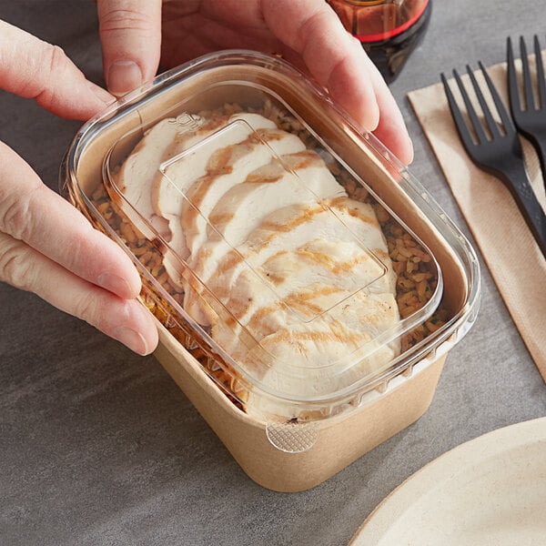 A person's hand holding a rectangular container of food.