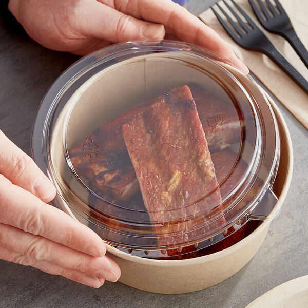 A hand holding a Choice round plastic take-out container filled with food.