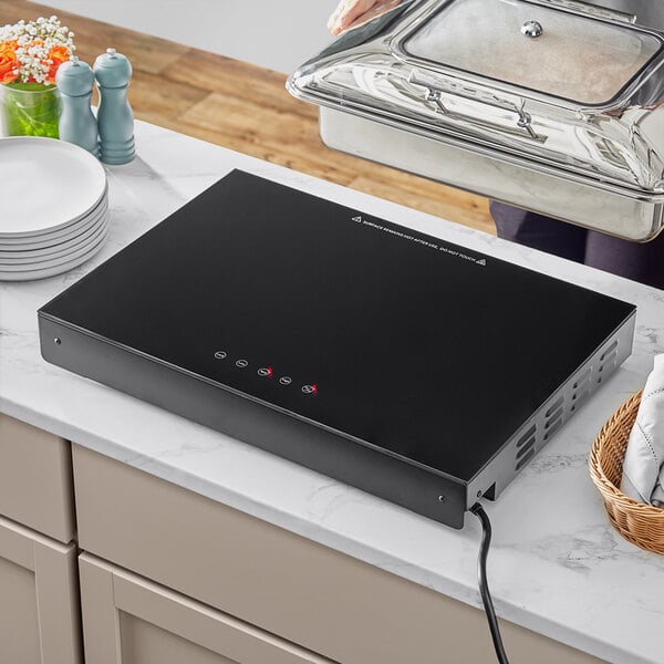 A black rectangular Avantco countertop induction warmer on a counter.