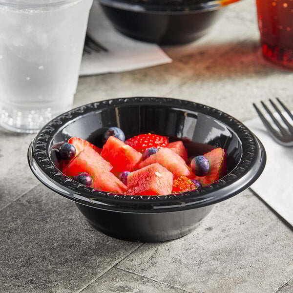 A black Huhtamaki Chinet bowl filled with watermelon and blueberries.