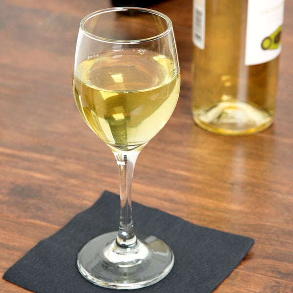 A Libbey white wine glass filled with white wine on a table.