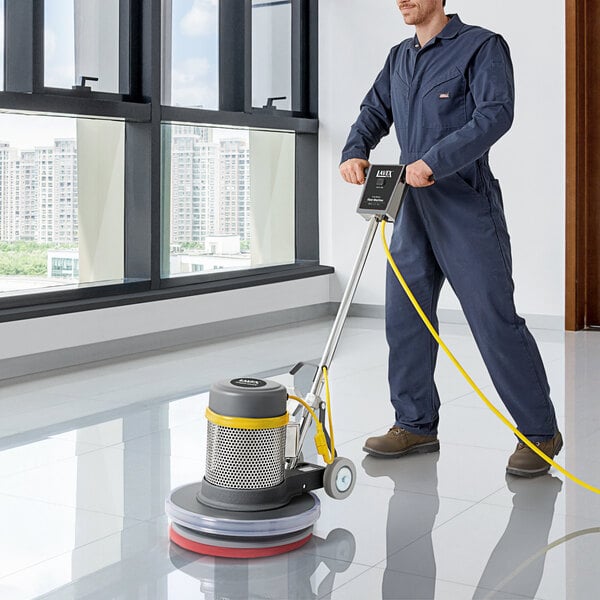 A man in a blue coverall using a Lavex Pro heavy-duty floor machine to clean a floor.