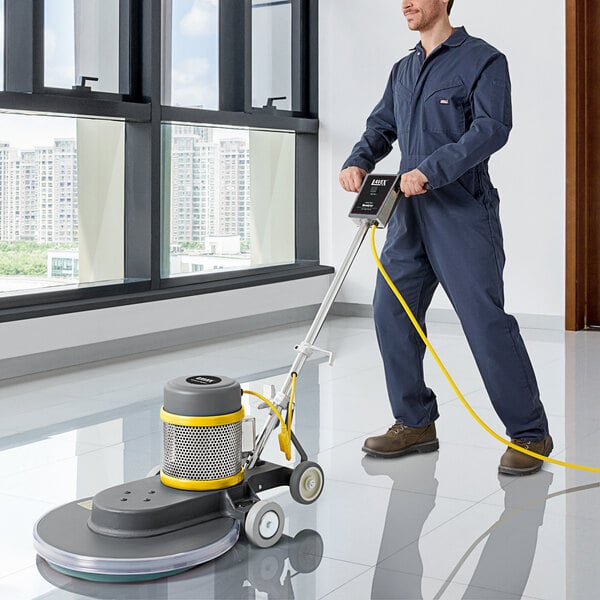 A man in coveralls using a Lavex Pro floor polisher to clean a floor.