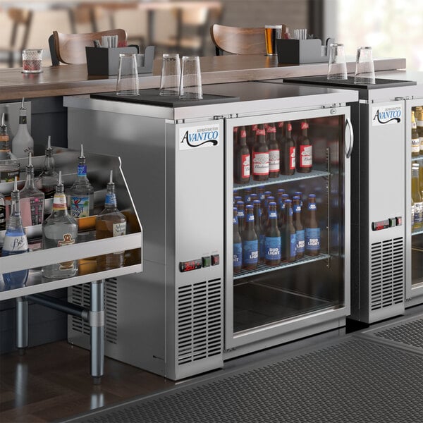 An Avantco back bar refrigerator on a counter with bottles of beer.