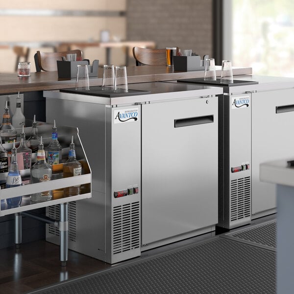 A group of Avantco stainless steel back bar refrigerators on a counter with bottles inside.