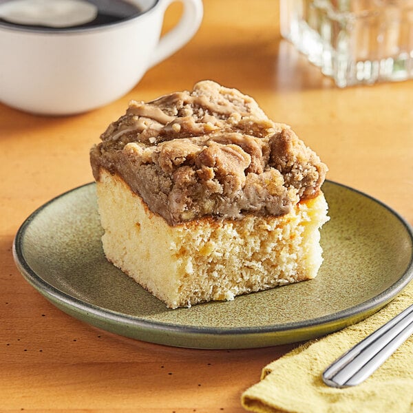 A slice of Hahn's Bakery caramel apple German crumb cake on a plate next to a cup of coffee.