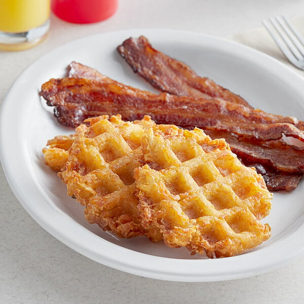 A plate of Lamb Weston Waffled Hash Brown Potatoes with bacon and waffles.