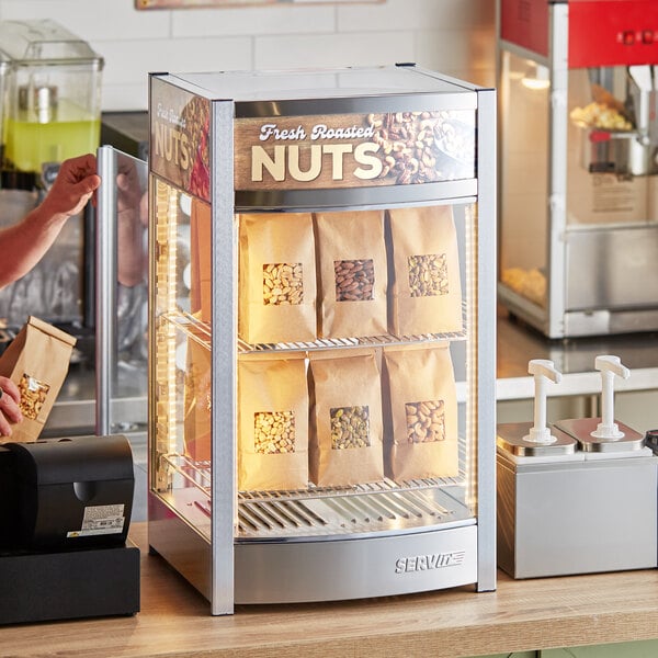 A ServIt countertop display warmer filled with bags of nuts.