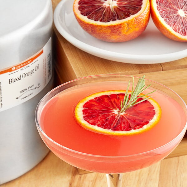 A glass of pink blood orange cocktail with a slice of blood orange on the rim.