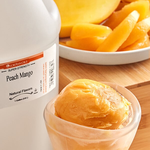 A bottle of LorAnn Oils Peach Mango flavoring next to a bowl of peaches.