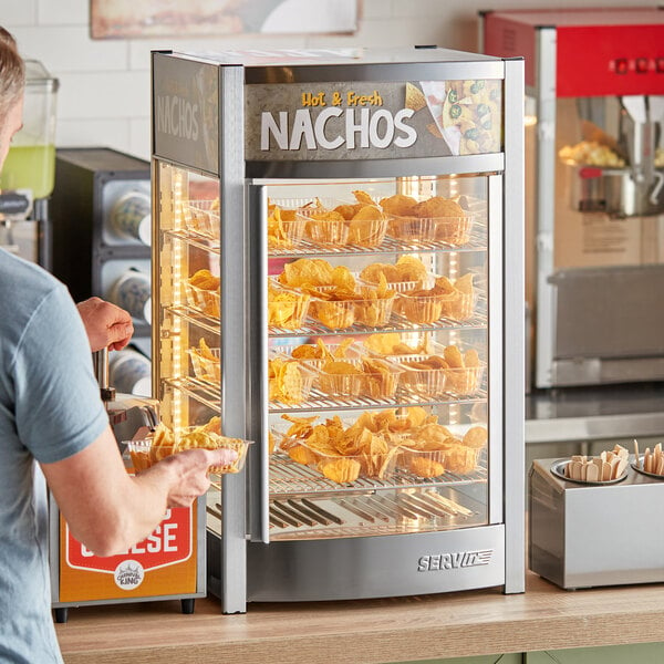 A man putting chips into a ServIt countertop display warmer.