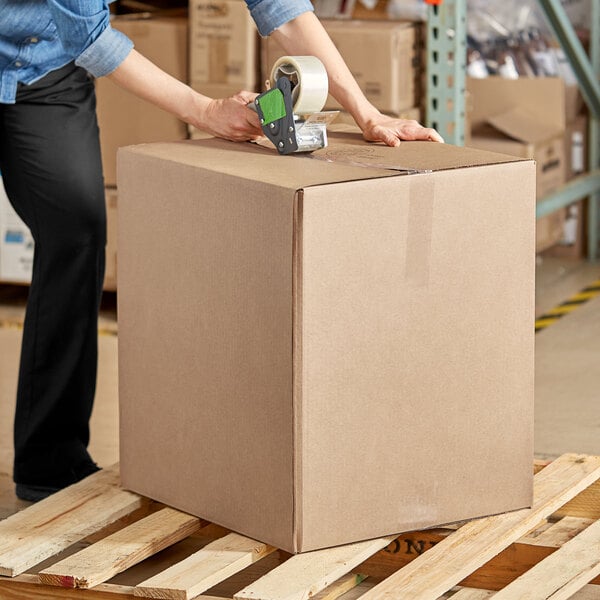 A woman using a box cutter to cut a Lavex shipping box.