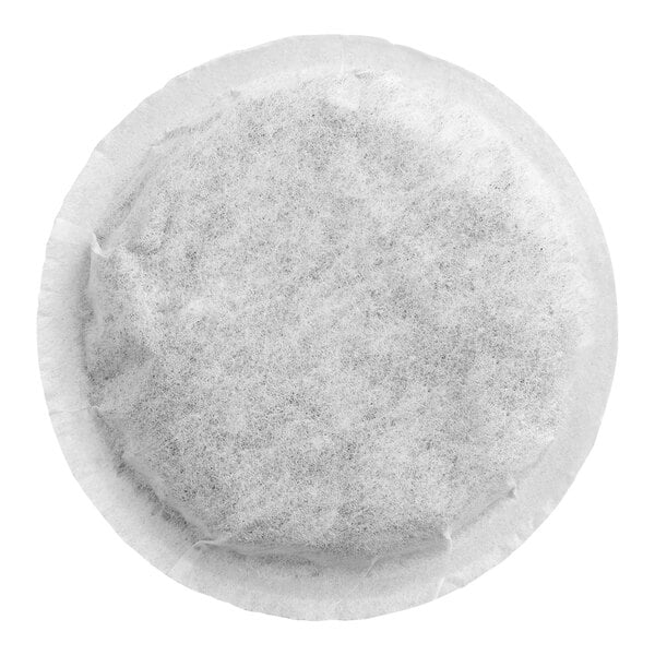 A round, flat, white filter pod containing a fine, dark substance, likely tea or coffee, viewed from above.