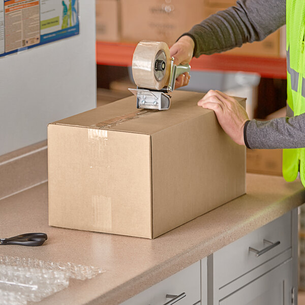 A person packing a Lavex Kraft corrugated shipping box.