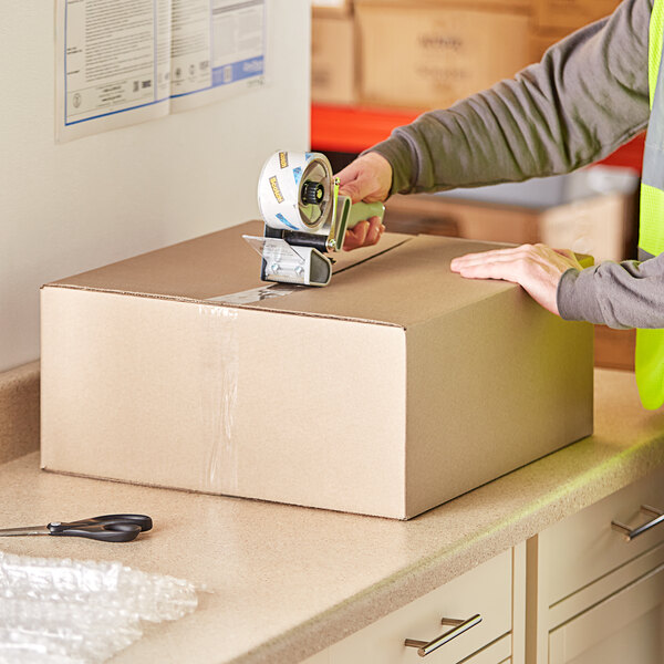 A person packing a Lavex cardboard shipping box.