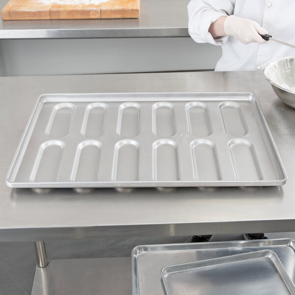 A person using a Chicago Metallic rounded end hoagie bun pan to prepare food.