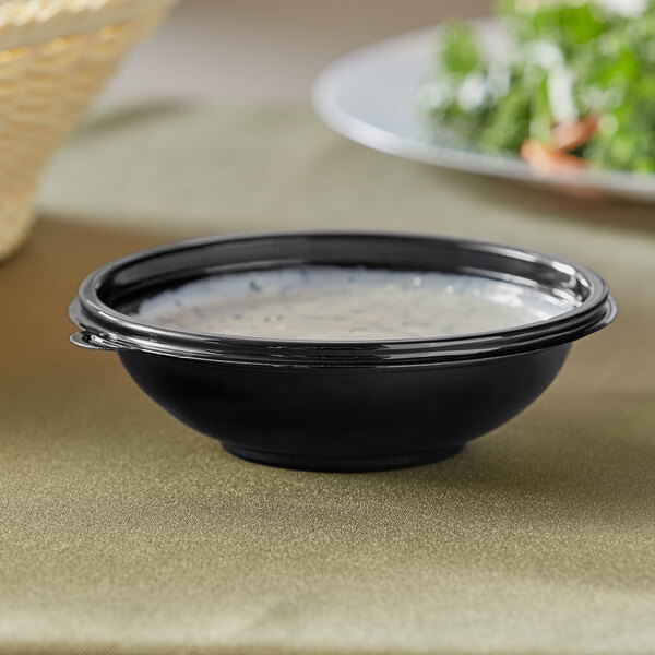 A black bowl of soup on a table.