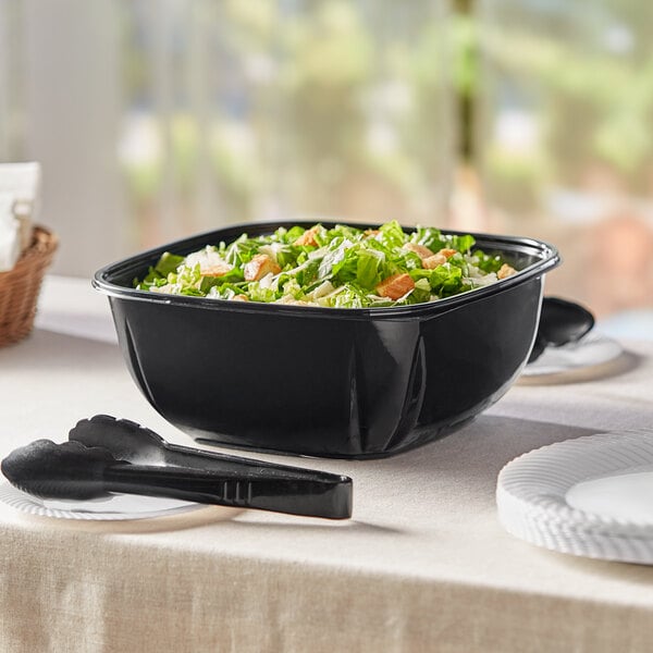 A bowl of salad in a black container.