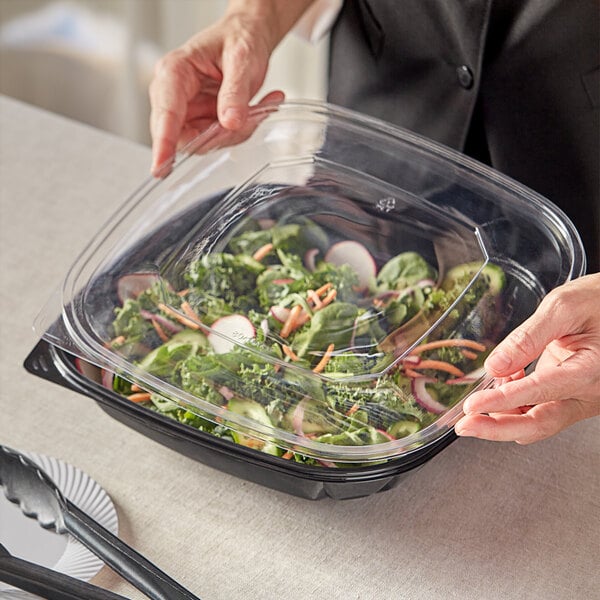 A person holding a Visions plastic container of food.