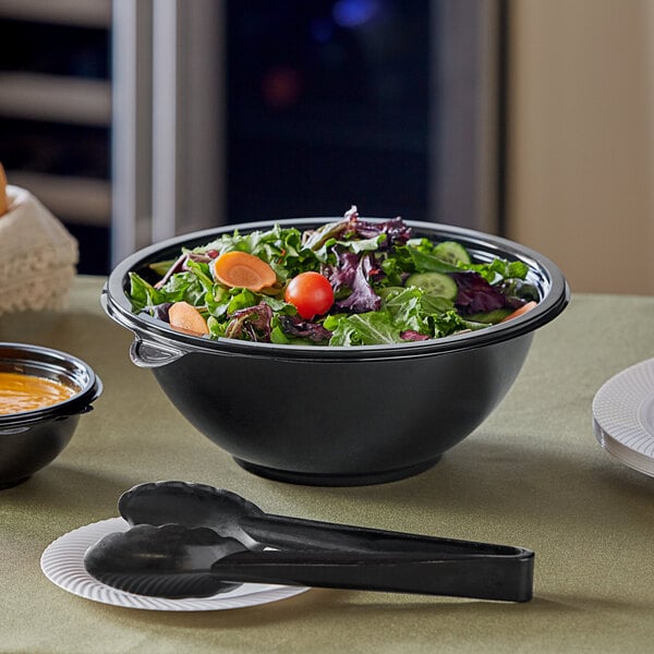 A black Visions catering bowl filled with salad and a spoon.