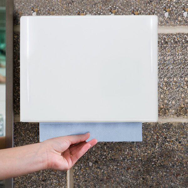 A white wall-mounted paper towel dispenser with a blue paper towel being pulled out.