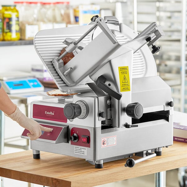 A woman using a Estella meat slicer on a deli counter.