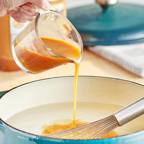 A person pouring Knorr Professional Ultimate Liquid Concentrated Chicken Base into a pot.