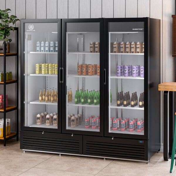 A large black refrigerated glass door merchandiser with three swing doors and LED lighting, stocked with assorted beverages.