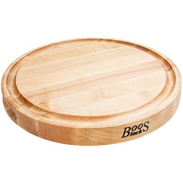 A John Boos round maple wood cutting board with grooves.