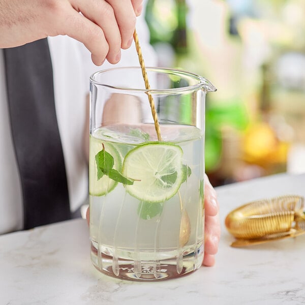 A bartender pouring a drink into a Barfly stirring glass.