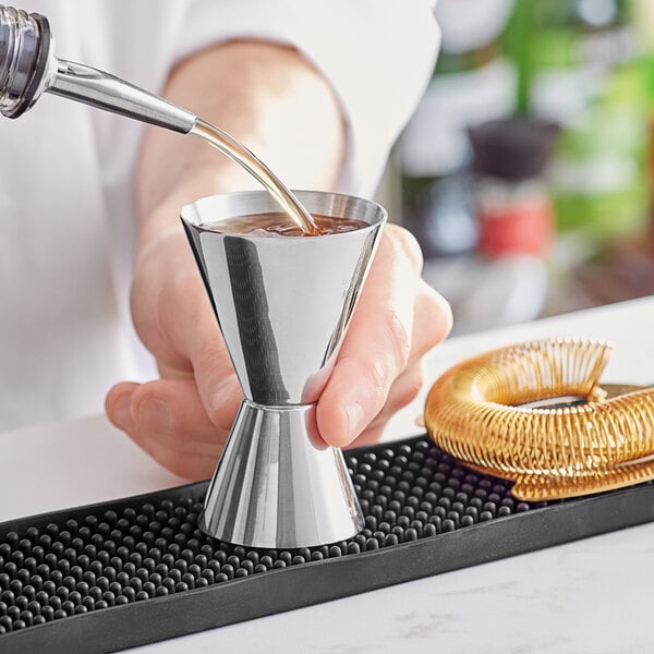 A bartender using a Barfly stainless steel jigger to pour liquid