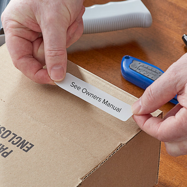 A person's hands putting a Lavex white label on a cardboard box.