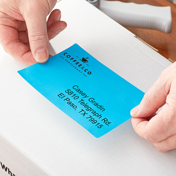 A person's hands using a Lavex blue thermal label on a white tube.