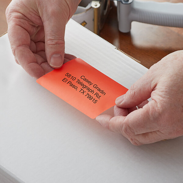 A person's hands holding a piece of paper with a Lavex red label on it.