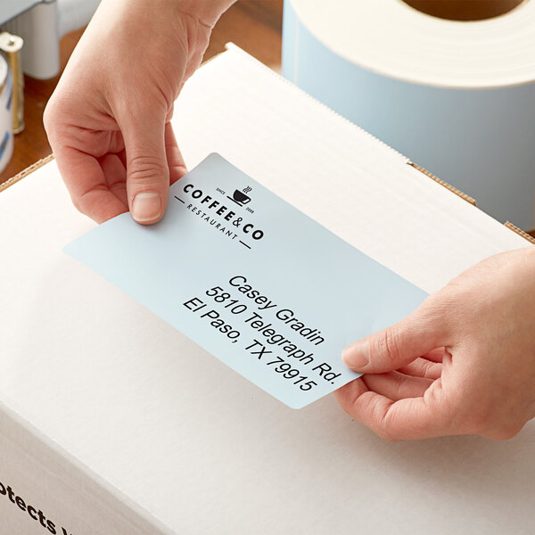 A person holding a box with a Lavex blue thermal transfer label on it.